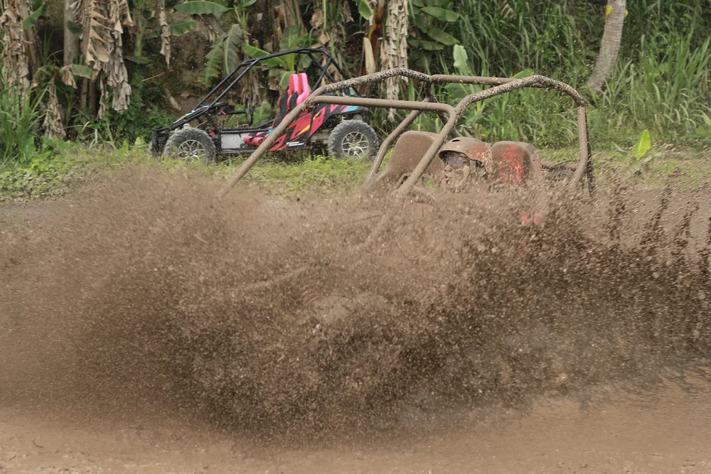 Massive mud explosion splashing beside high-speed buggy on the track