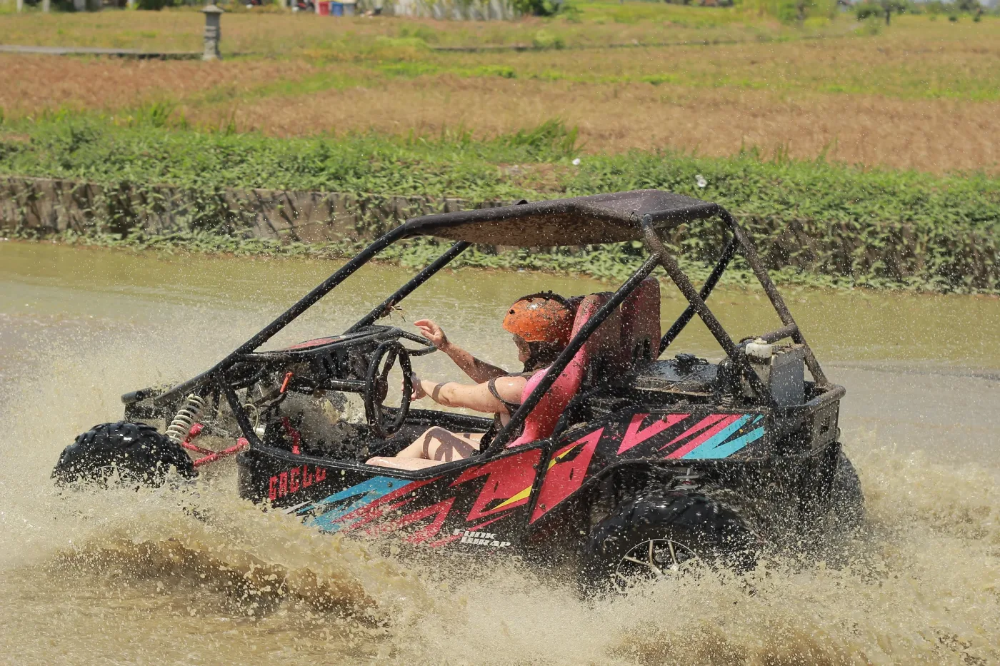 Buggy throwing spray through a muddy water section